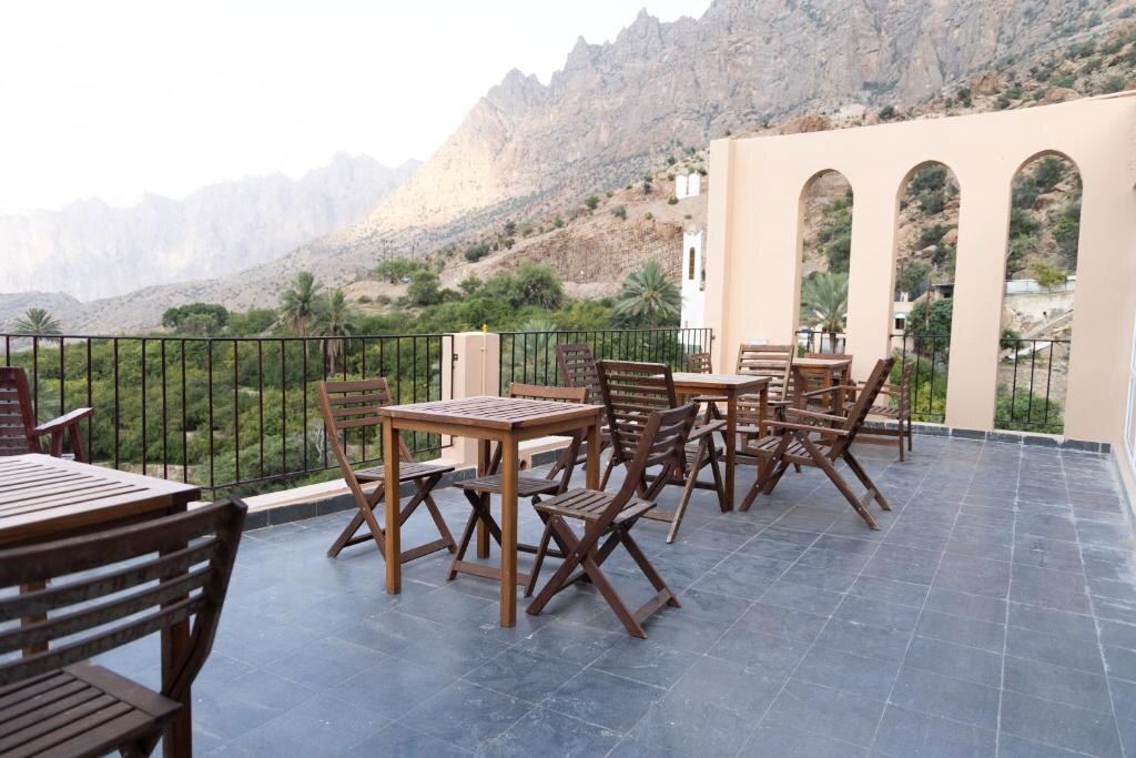 Mountain terrace with tables and arched guest-house facade